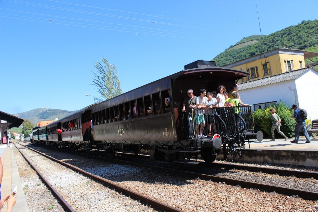Comboio histórico com passageiros, parado na estação.